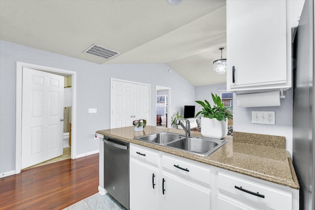 kitchen featuring visible vents, lofted ceiling, stainless steel dishwasher, white cabinets, and a sink