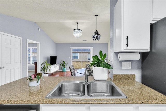 kitchen featuring lofted ceiling, a sink, dishwasher, white cabinetry, and open floor plan