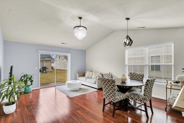 dining room featuring visible vents, lofted ceiling, an inviting chandelier, and hardwood / wood-style floors