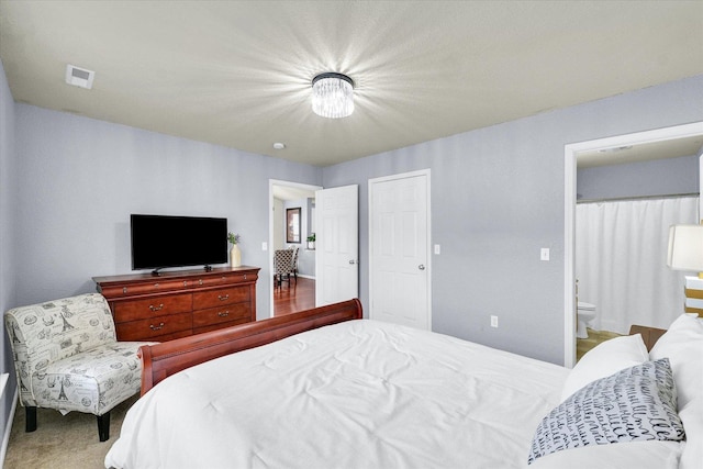 carpeted bedroom featuring visible vents, a closet, and ensuite bath