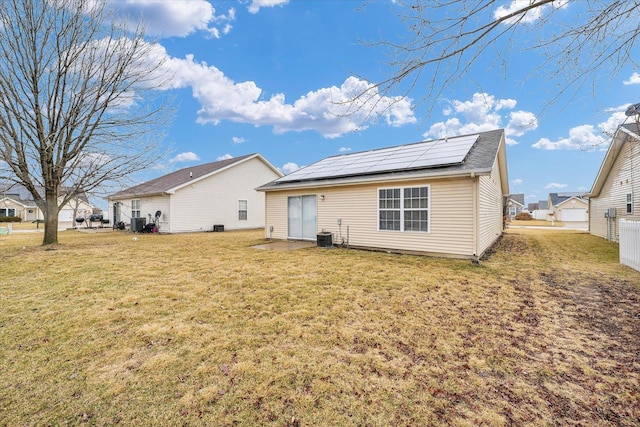 back of property featuring cooling unit, a lawn, and roof mounted solar panels