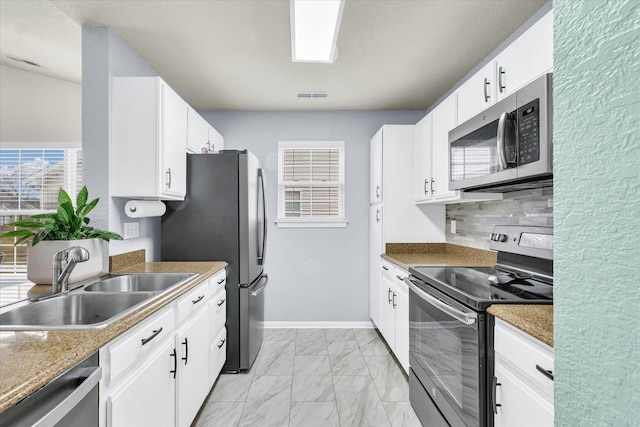 kitchen featuring visible vents, marble finish floor, a sink, backsplash, and appliances with stainless steel finishes