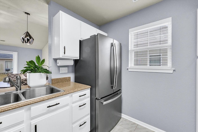 kitchen featuring marble finish floor, a sink, white cabinetry, freestanding refrigerator, and baseboards