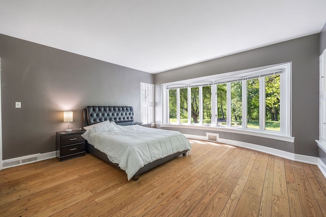 bedroom featuring visible vents, light wood-style flooring, and baseboards