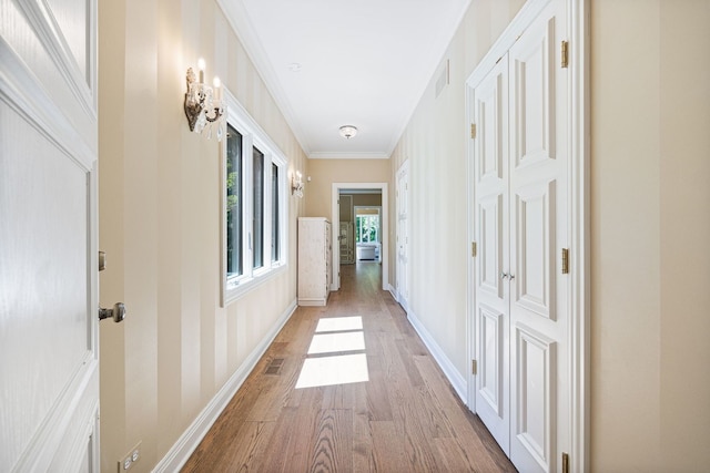 hall featuring baseboards, visible vents, and light wood-style floors