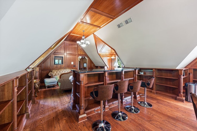 bar with vaulted ceiling, a bar, hardwood / wood-style floors, and visible vents