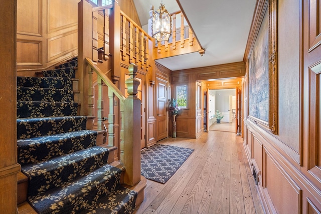 entrance foyer featuring visible vents, a decorative wall, stairway, a chandelier, and light wood-type flooring