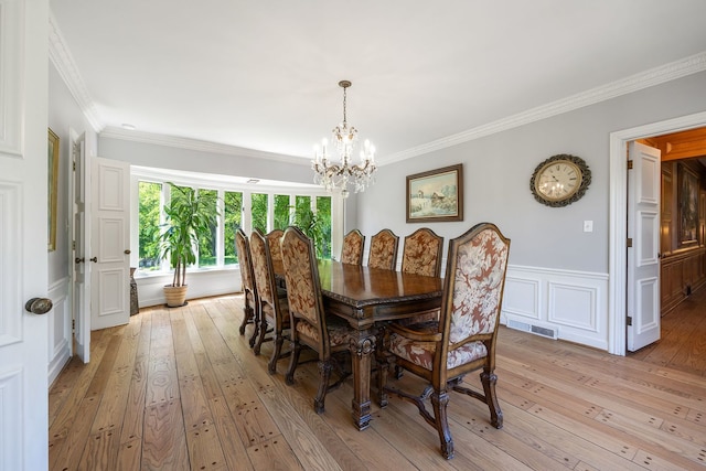 dining area featuring a wainscoted wall, visible vents, crown molding, and light wood finished floors