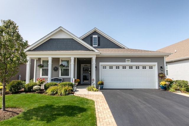 craftsman house with a garage, aphalt driveway, a front lawn, and a porch