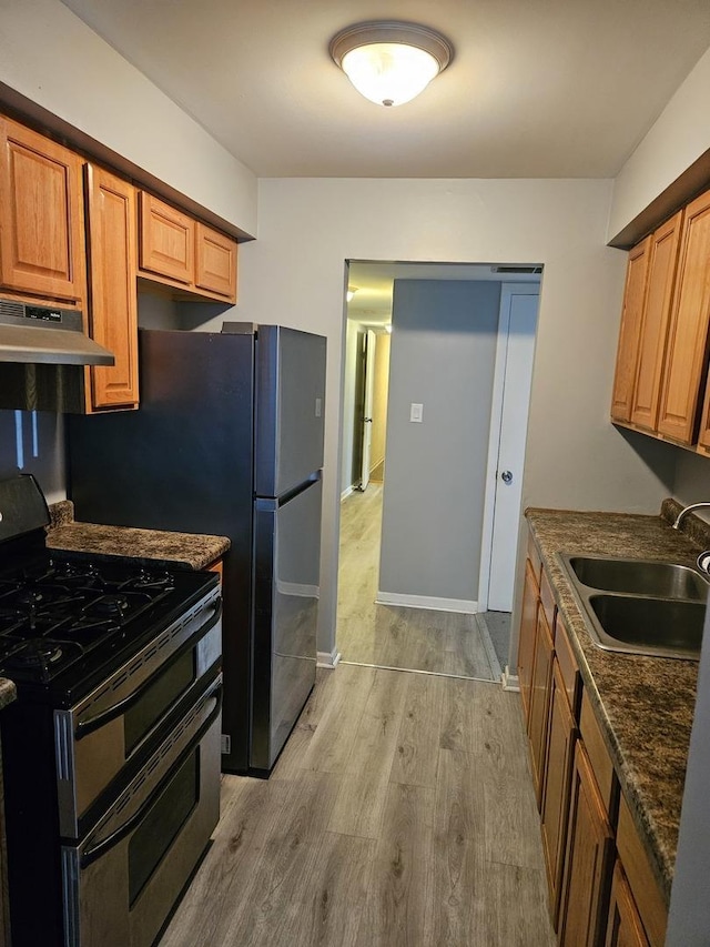 kitchen with range with two ovens, light wood finished floors, a sink, under cabinet range hood, and baseboards