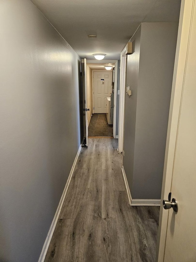 hallway with dark wood-style flooring and baseboards