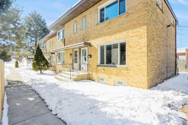 snow covered house featuring crawl space and brick siding