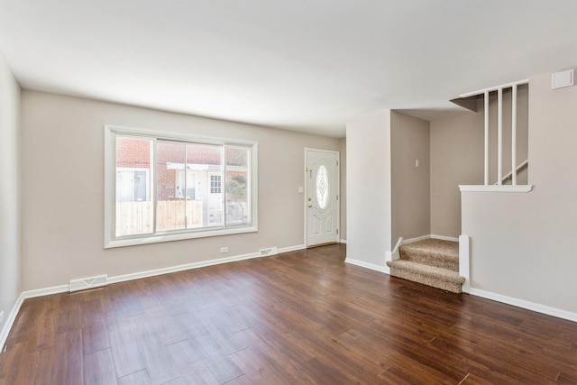 foyer entrance featuring dark wood-type flooring, visible vents, stairway, and baseboards