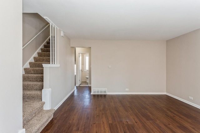 unfurnished room with stairway, wood finished floors, visible vents, and baseboards