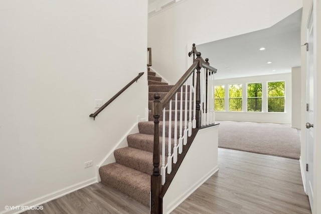 staircase featuring baseboards, wood finished floors, and recessed lighting