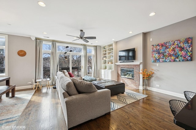 living area with built in shelves, recessed lighting, wood finished floors, baseboards, and a brick fireplace