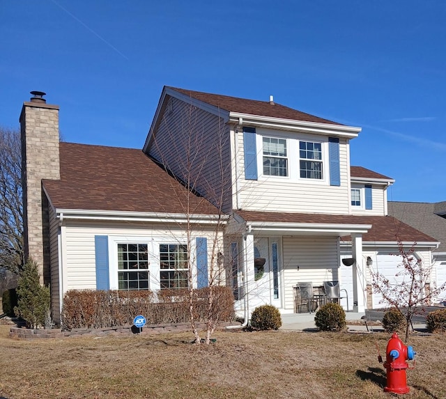 traditional-style home with a shingled roof, covered porch, and a chimney