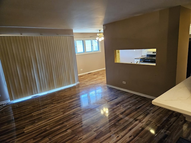 spare room with ceiling fan, dark wood finished floors, and baseboards