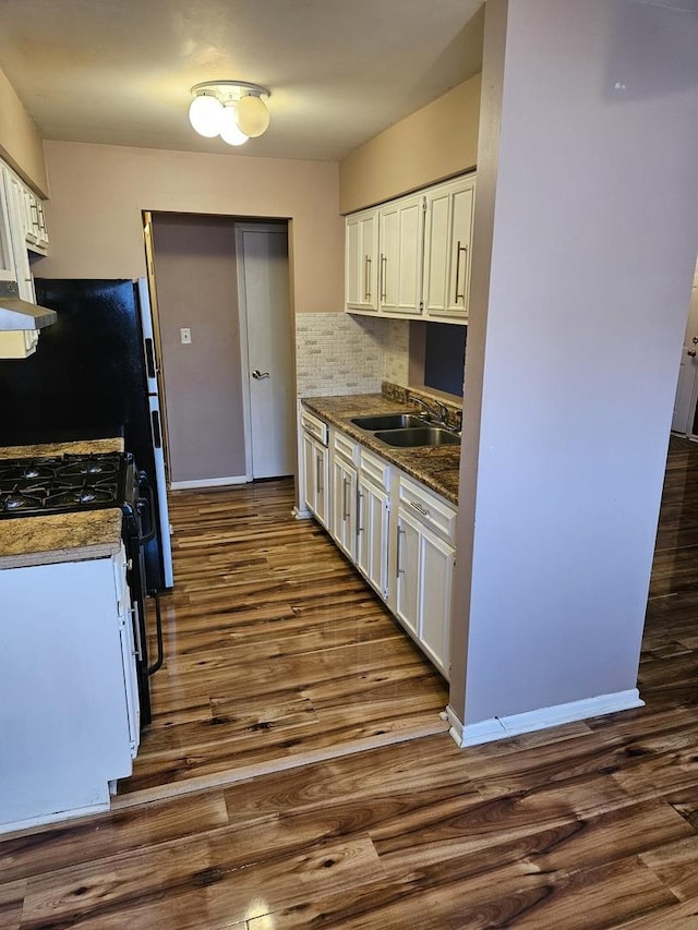 kitchen featuring dark wood-style floors, white cabinets, a sink, and gas stove