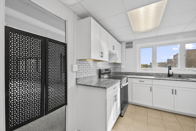 kitchen with decorative backsplash, white cabinets, stainless steel electric stove, a paneled ceiling, and a sink