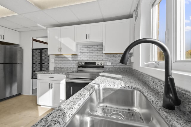 kitchen with stainless steel appliances, a drop ceiling, backsplash, and white cabinetry