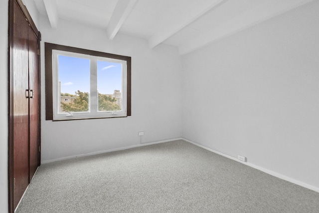 unfurnished bedroom with carpet, beam ceiling, and baseboards