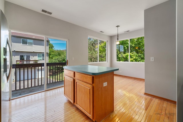 1061 Chadwick Dr, Grayslake, IL 60030 - kitchen with light wood-style flooring, dark countertops, a center island, stainless steel fridge with ice dispenser, and pendant lighting