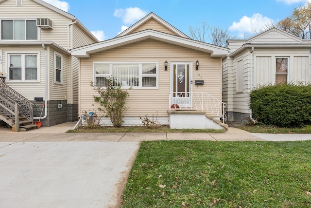 view of front of property featuring an AC wall unit and a front lawn