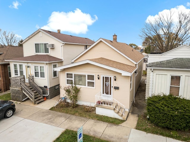 view of front of home featuring a wall mounted air conditioner and roof with shingles