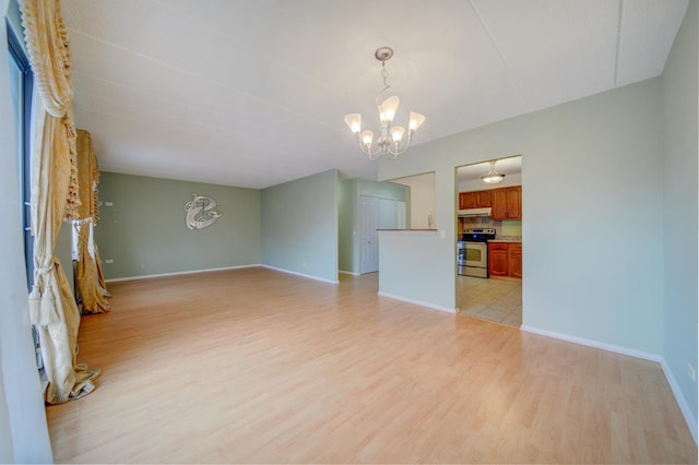 unfurnished room with a chandelier, light wood-type flooring, and baseboards