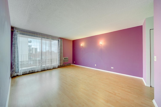 unfurnished room featuring a textured ceiling, baseboards, and wood finished floors