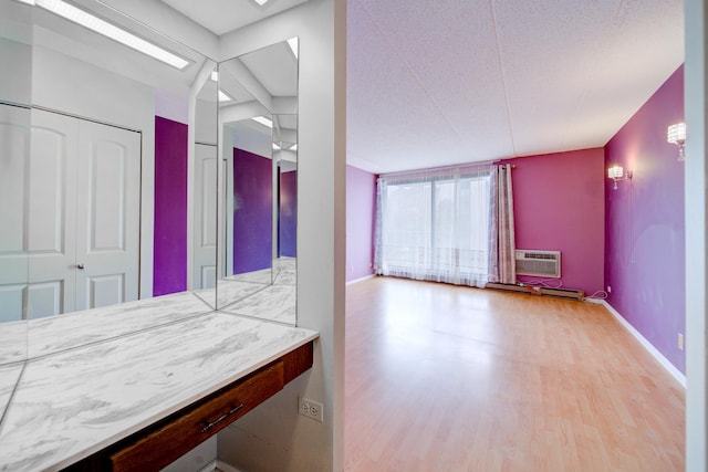 bathroom featuring an AC wall unit, baseboards, and wood finished floors