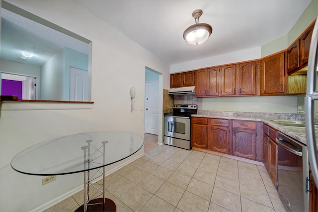 kitchen with under cabinet range hood, light tile patterned floors, appliances with stainless steel finishes, and light countertops