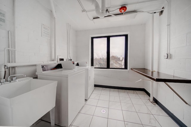 shared laundry area with washer and clothes dryer, a sink, and concrete block wall