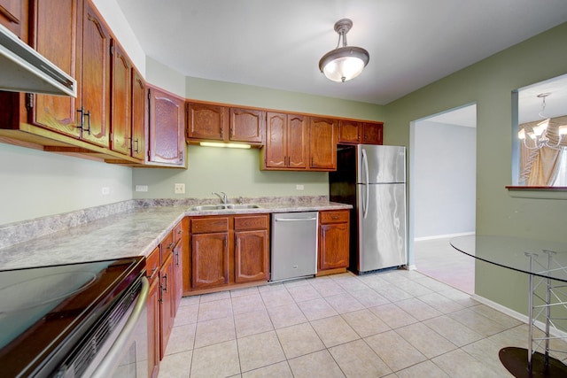 kitchen with an inviting chandelier, stainless steel appliances, light countertops, under cabinet range hood, and a sink