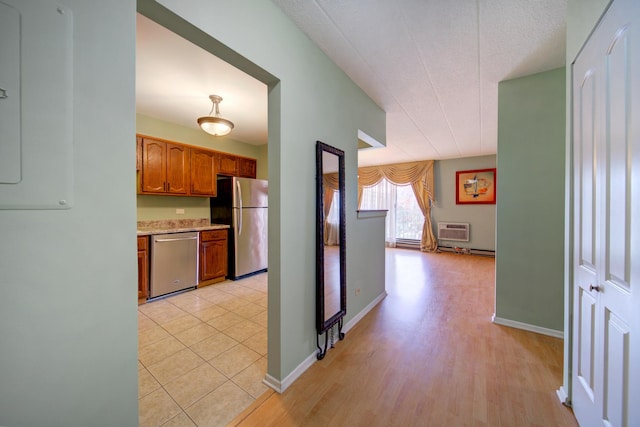 kitchen with appliances with stainless steel finishes, brown cabinetry, light countertops, and baseboards