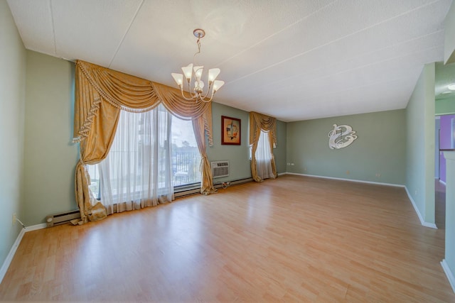 spare room with baseboards, a chandelier, and wood finished floors