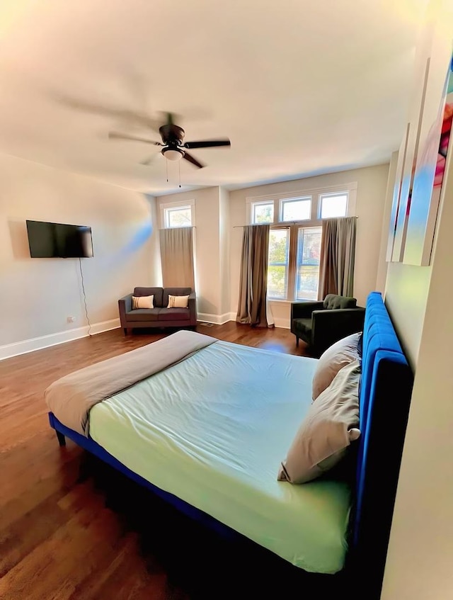 bedroom featuring ceiling fan, baseboards, and wood finished floors