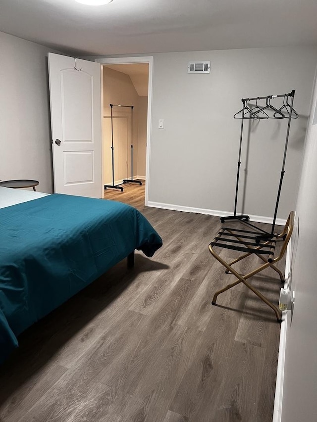 bedroom featuring visible vents, baseboards, and wood finished floors