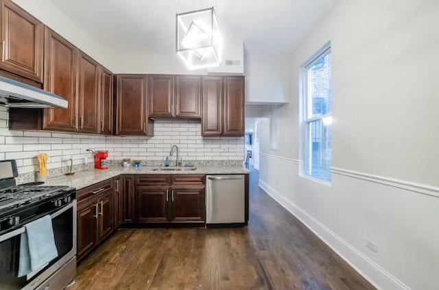 kitchen with stainless steel appliances, dark wood-type flooring, a sink, and tasteful backsplash