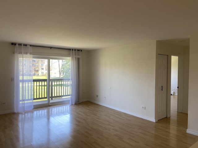 spare room with baseboards and wood finished floors