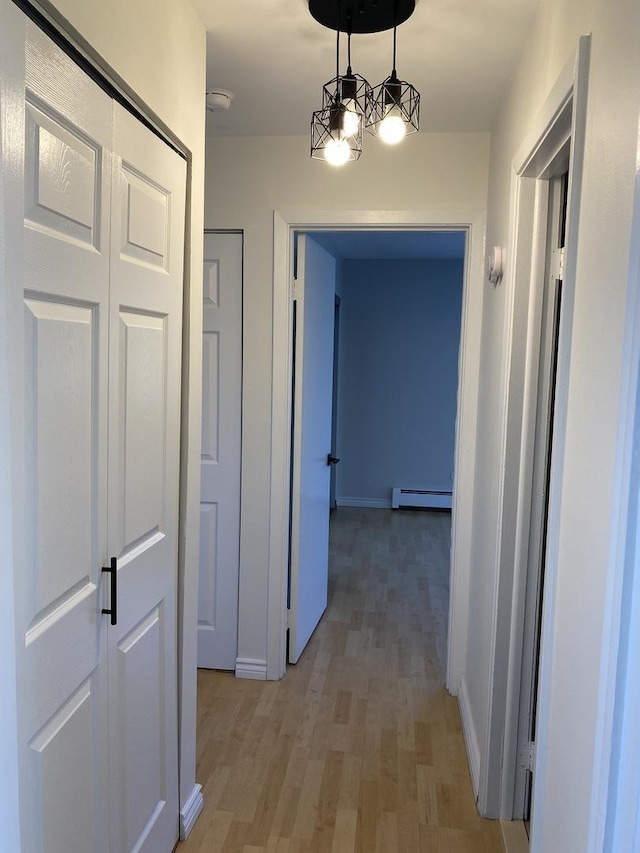 hallway with baseboards, baseboard heating, and light wood-style floors