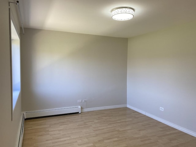 spare room featuring a baseboard radiator, light wood-style flooring, baseboards, and baseboard heating