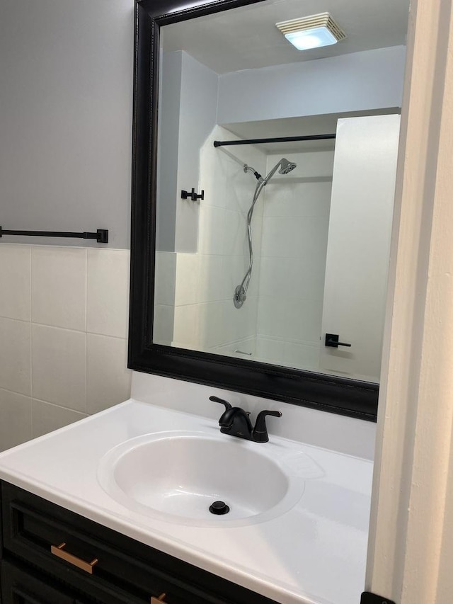 full bathroom featuring tile walls, vanity, and walk in shower