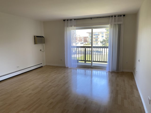 unfurnished room with a baseboard radiator, baseboards, and wood finished floors