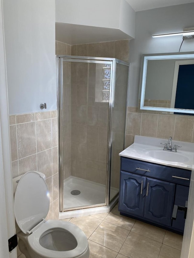 full bathroom with toilet, vanity, tile walls, a shower stall, and tile patterned floors