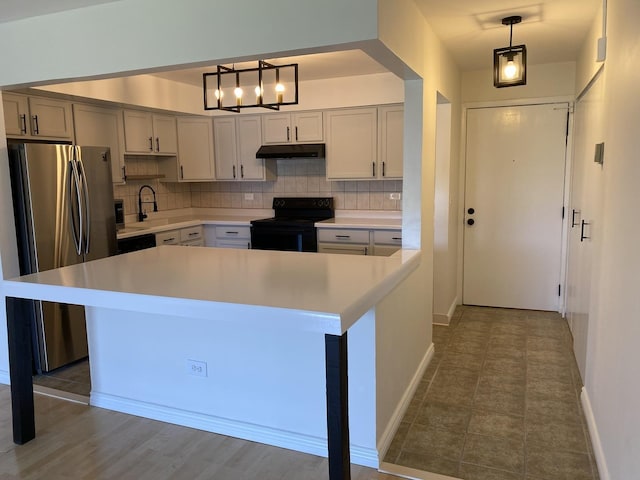 kitchen featuring tasteful backsplash, light countertops, freestanding refrigerator, black range with electric cooktop, and under cabinet range hood