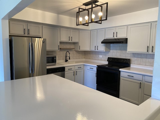 kitchen with light countertops, backsplash, appliances with stainless steel finishes, a sink, and under cabinet range hood