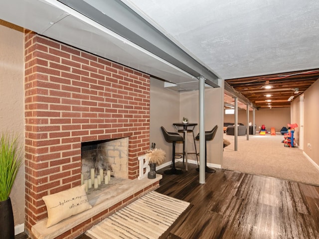 finished below grade area featuring baseboards, wood finished floors, and a fireplace