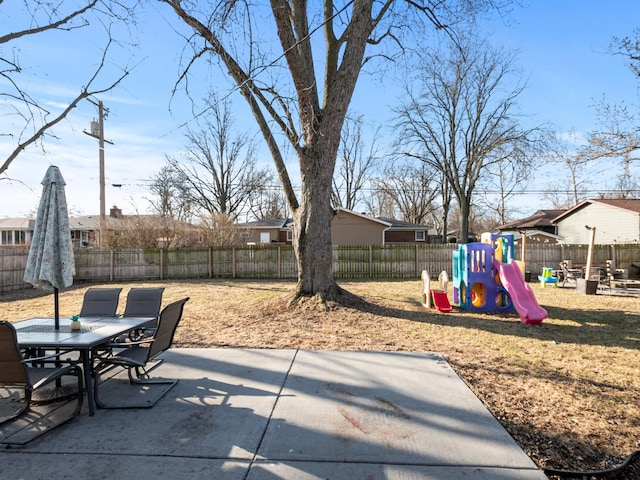 view of patio featuring outdoor dining space, a playground, and a fenced backyard